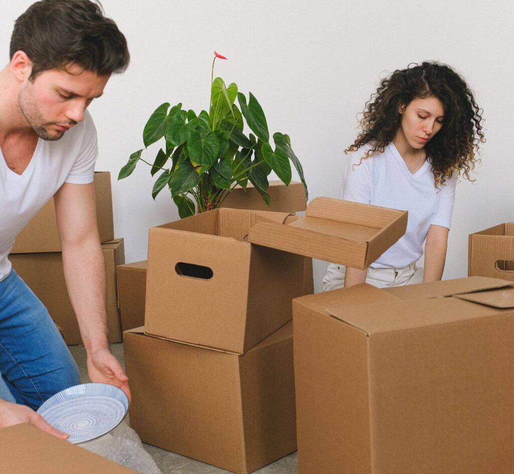 A man and woman are carrying boxes into a room