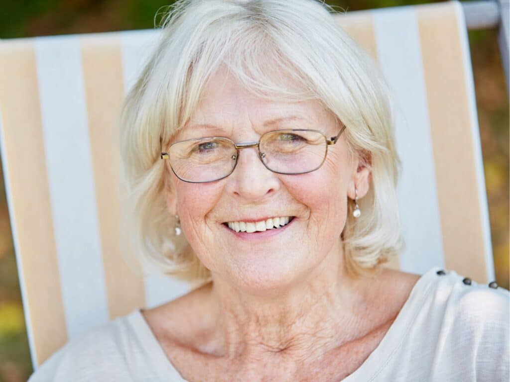 A woman wearing glasses sits comfortably in a chair